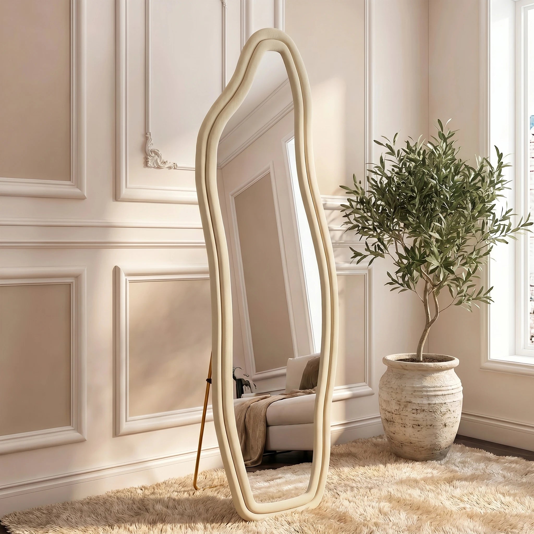 Miroir mural ondulé Nesty - Cadre écru dans une pièce aux boiseries blanches, à côté d'un olivier en pot
