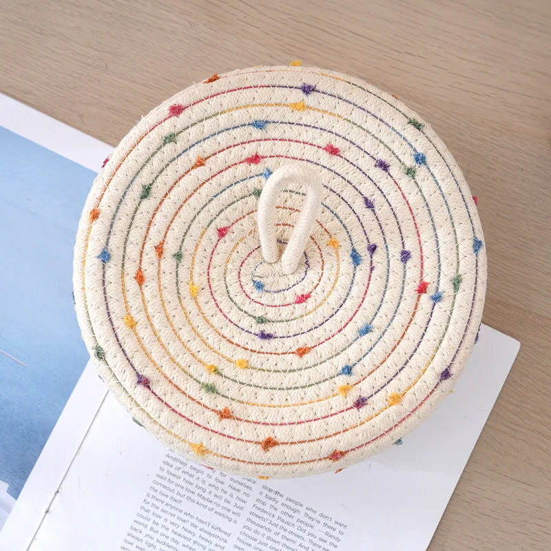 Panier de rangement tressé en corde de coton avec couvercle Nesty, vue de dessus du couvercle à surpiqûres multicolores, posé sur un livre