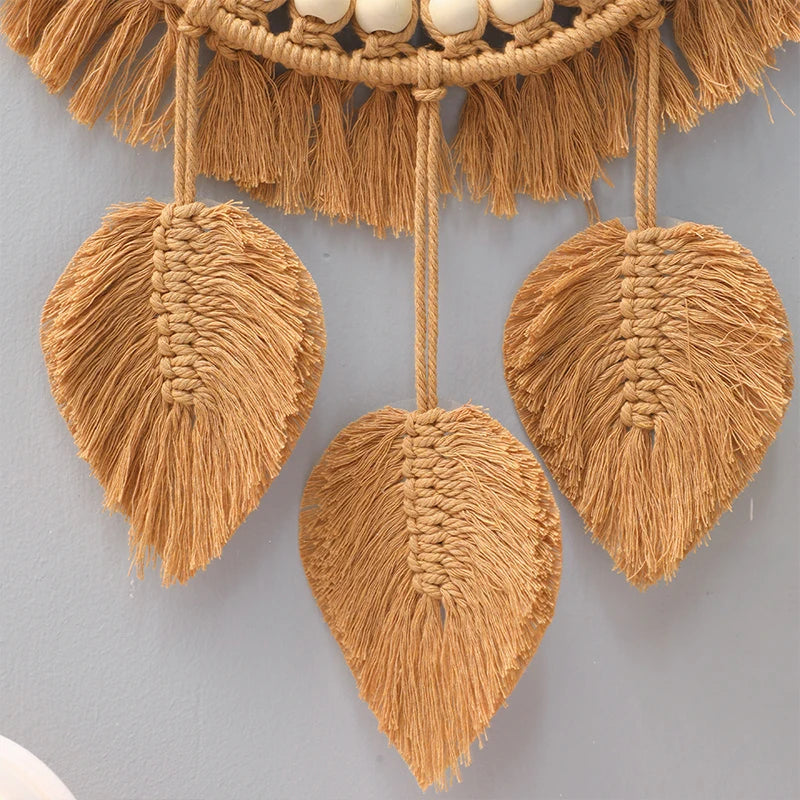 Trois plumes tressées en macramé suspendues sous le miroir, gros plan sur le tissage - Nesty