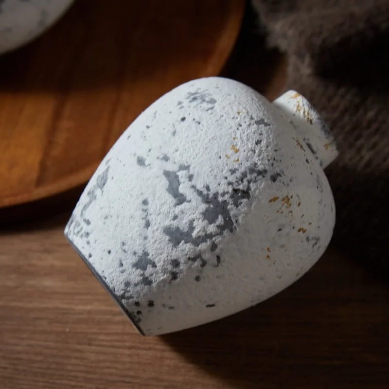 Vase en céramique fait main, esprit nostalgique Nesty, gros plan sur un petit vase effet pierre tacheté blanc et gris, posé sur le flanc