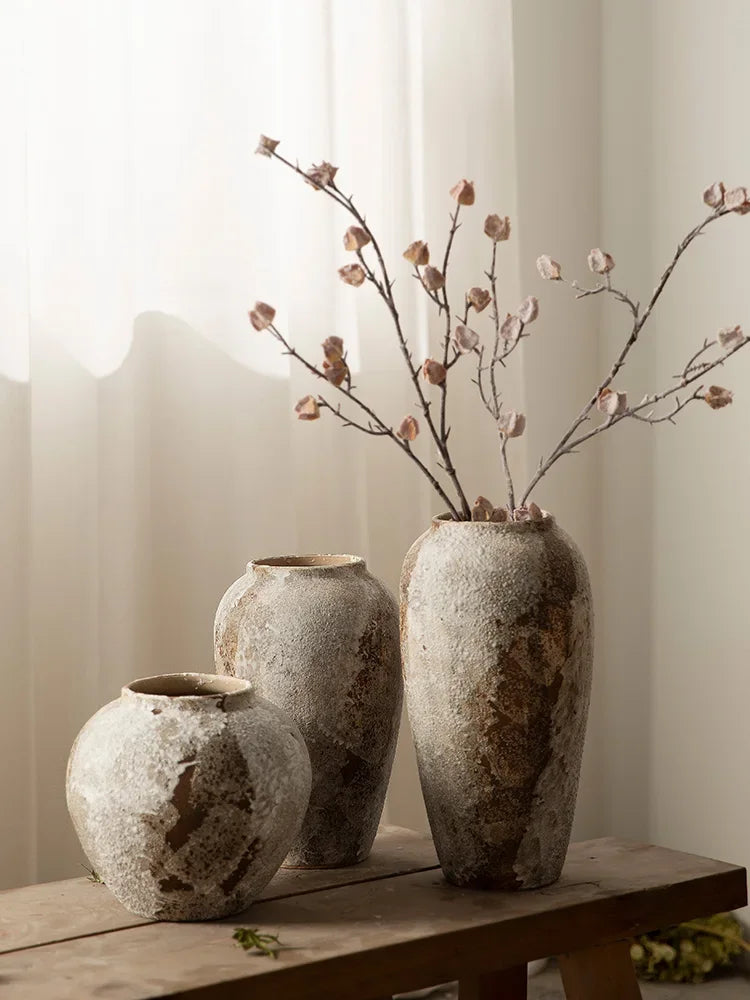 Vase en poterie mouchetée — esprit rétro chinois - Nesty - Trois tailles alignées avec rameaux fleuris roses, sur banc en bois devant un voilage