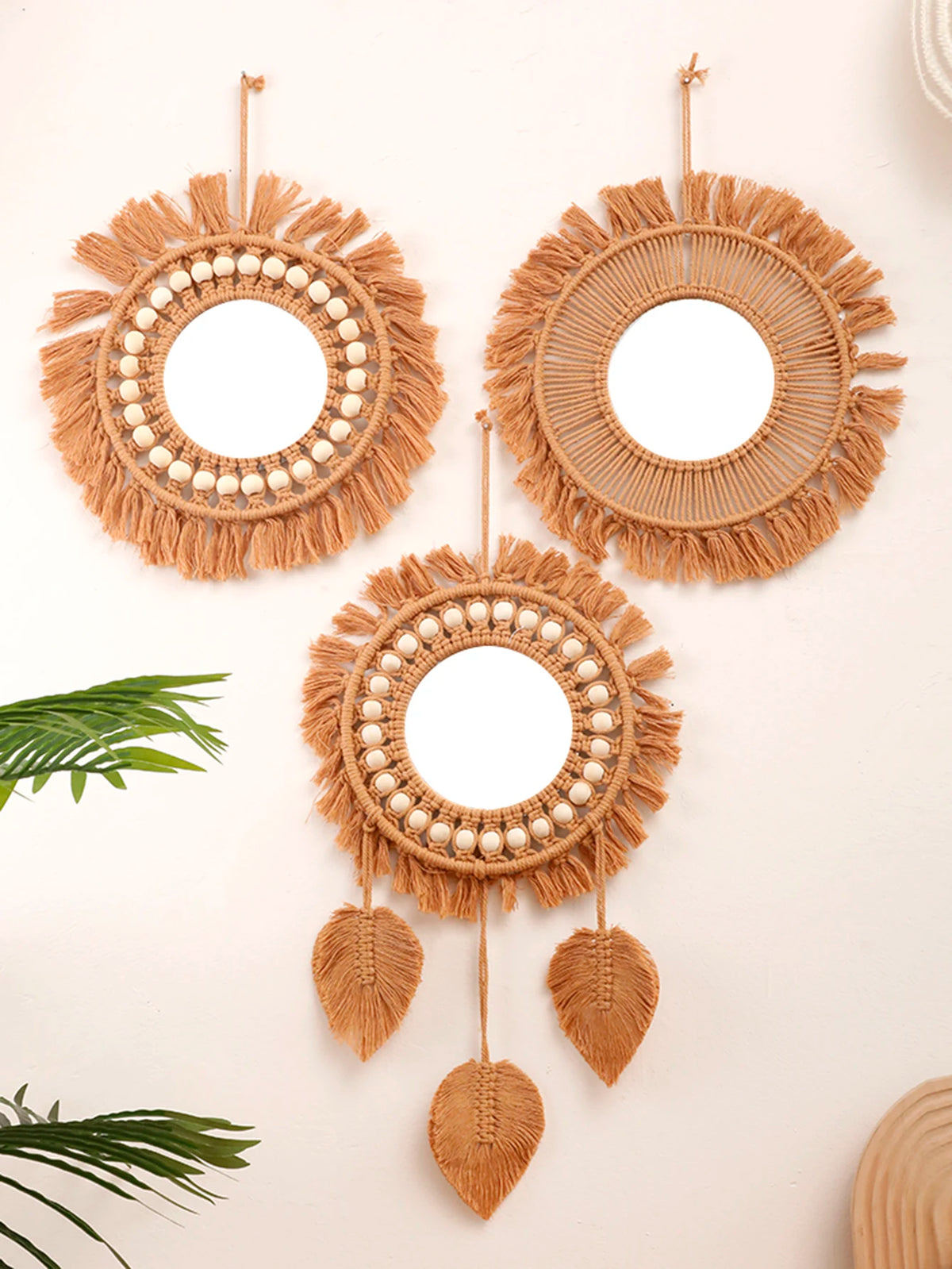Miroir rond tissé main Nesty - Trois modèles en macramé sur mur beige : perles de bois, franges et feuilles tressées