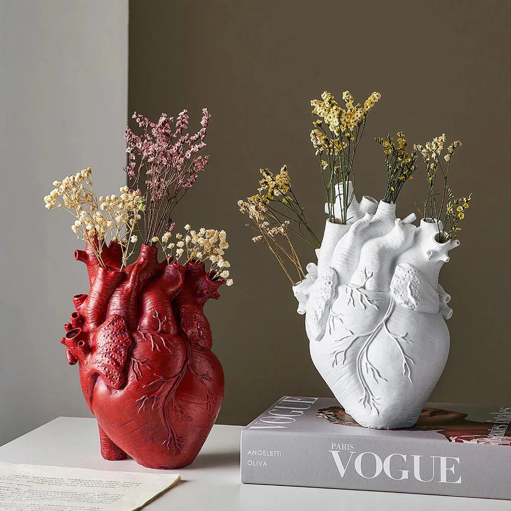 Vase en résine forme cœur, style nordique - Nesty - Coloris rouge et blanc côte à côte avec fleurs séchées jaunes et roses, posés sur des livres empilés