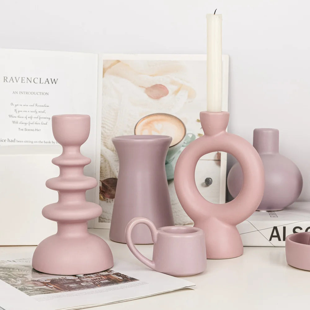 Collection de bougeoirs et vases en céramique rose poudré galbés, formes torsadée, anneau et pichet, sur bureau avec livres - Nesty