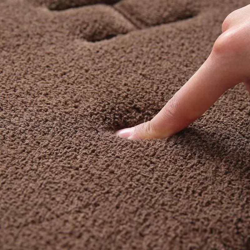 Tapis de bain moelleux en mousse à mémoire de forme - Nesty, gros plan sur un doigt enfoncé dans la mousse à mémoire de forme brune, démonstration de la texture moelleuse