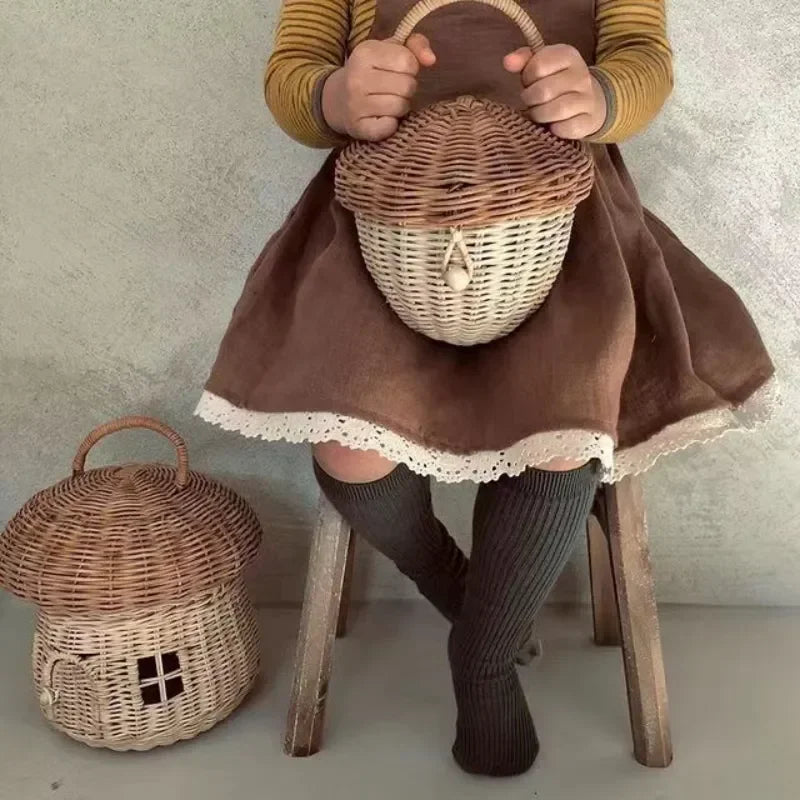 Petit panier tressé en osier forme champignon, panier décoratif Nesty, enfant assis tenant un petit panier brun en forme de gland, second panier au sol