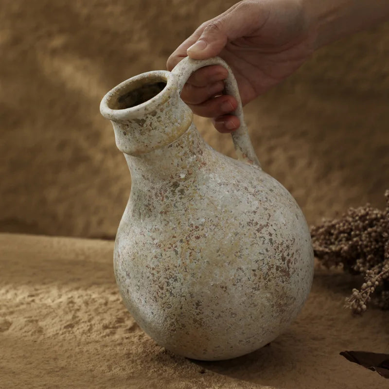 Vase en céramique style wabi-sabi pour fleurs séchées Nesty, main tenant la cruche par son anse, gros plan sur le col patiné