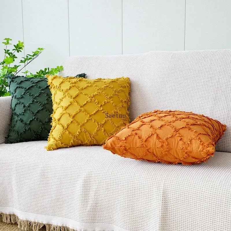 Housse de coussin en coton et lin, motif losange tricoté Nesty, trois housses de coussin à texture en losanges effilochés, coloris vert sapin, moutarde et orange, sur canapé avec plante verte