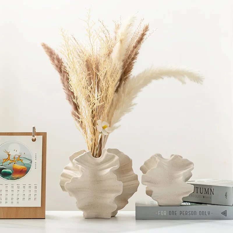 Vase en céramique à motifs ondulés, forme pétale Nesty, deux vases de tailles différentes garnis de graminées séchées, posés sur des livres