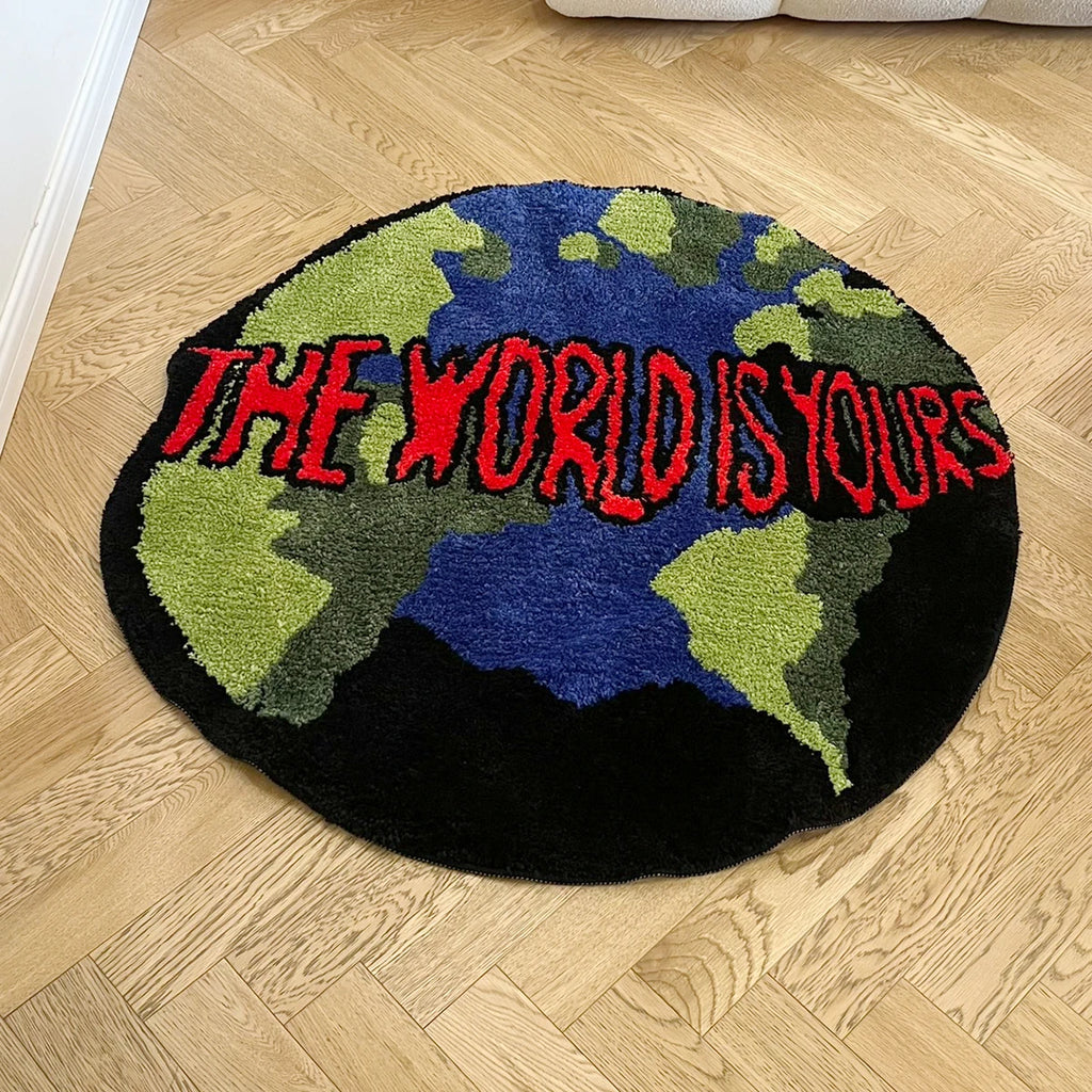 Tapis rond en acrylique — motif animalier - Nesty, vue rapprochée du tapis rond motif carte du monde et inscription rouge, posé sur un parquet clair