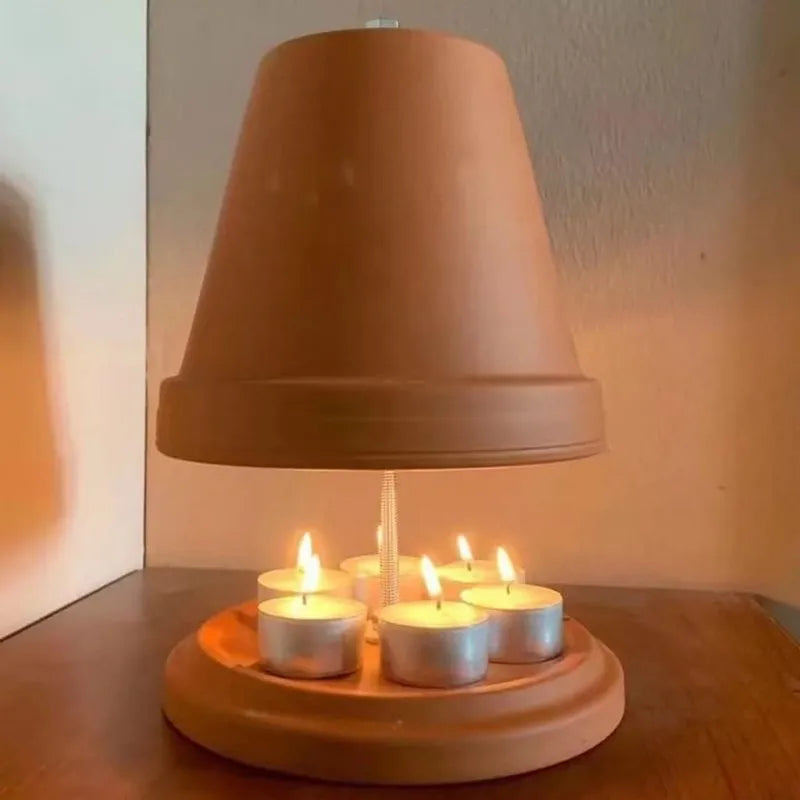 Chauffe-plat en terre cuite Nesty - Modèle allumé diffusant une lumière chaude au-dessus des bougies chauffe-plat