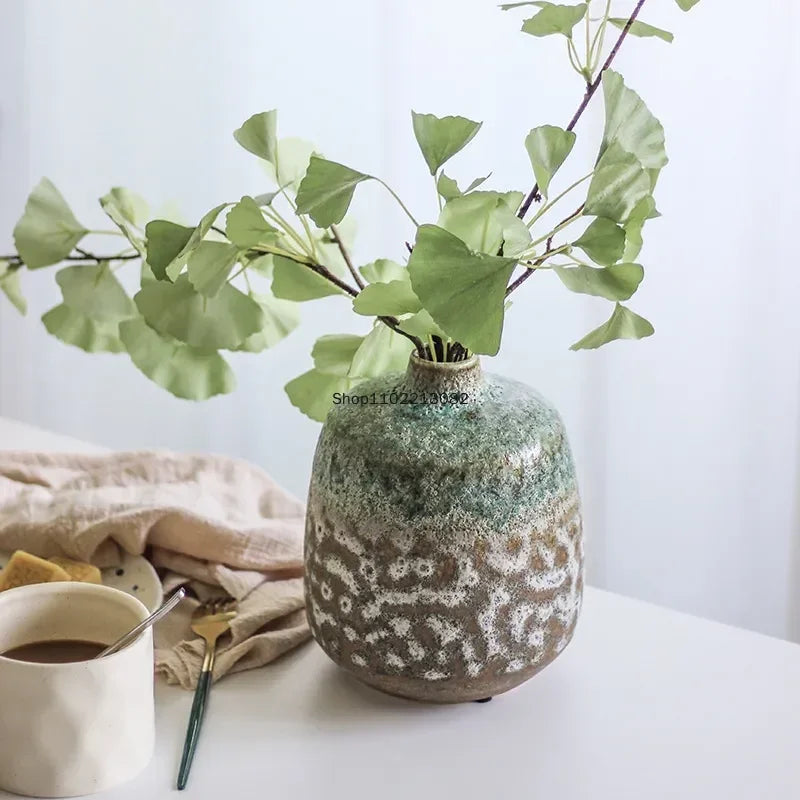 Vase en céramique effet bulles Nesty - Forme ovoïde avec branche de ginkgo, posé sur table près d'une tasse de café