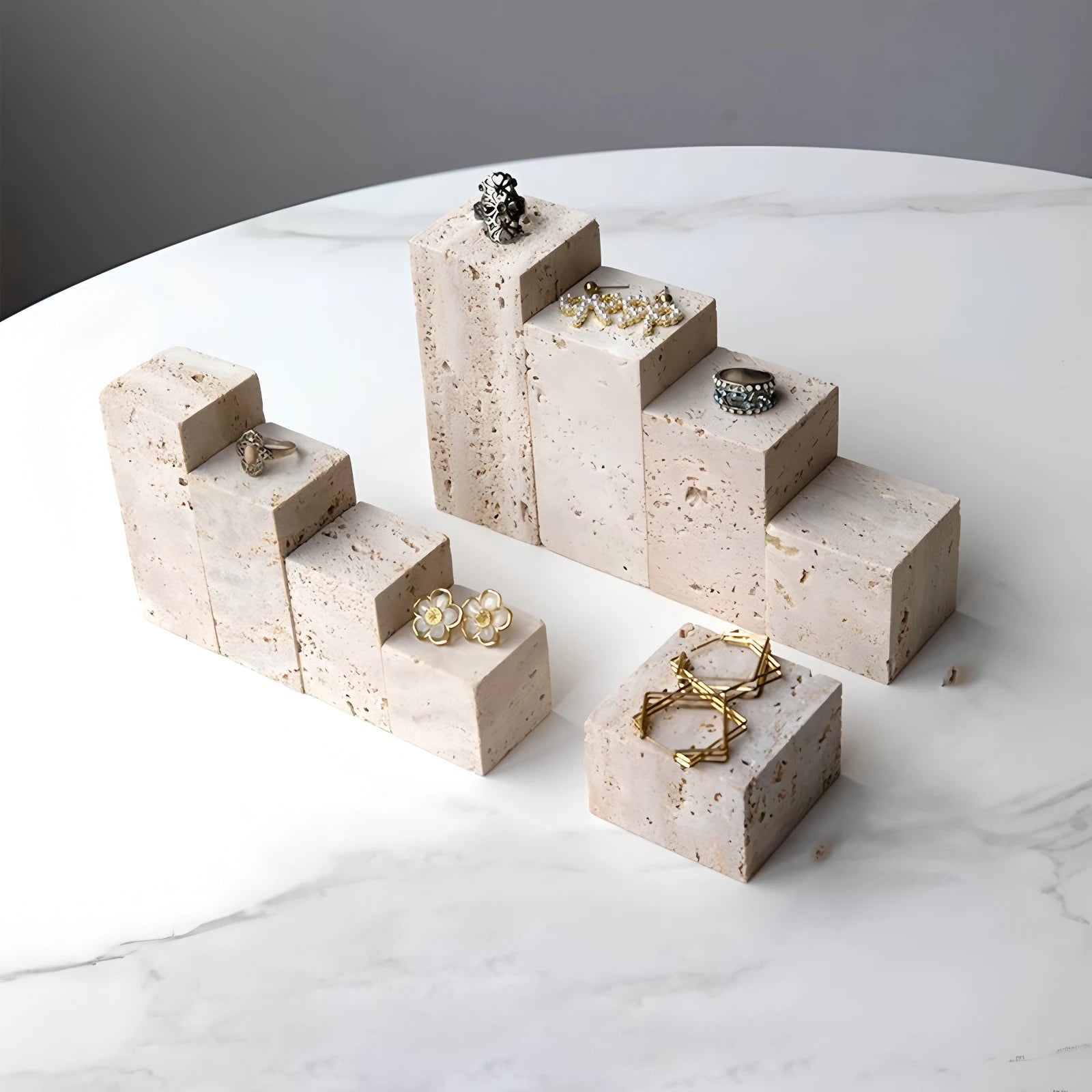 Plateau vide-poche en pierre naturelle Nesty - Gros plan sur les blocs en travertin en escalier avec bagues et boucles d'oreilles
