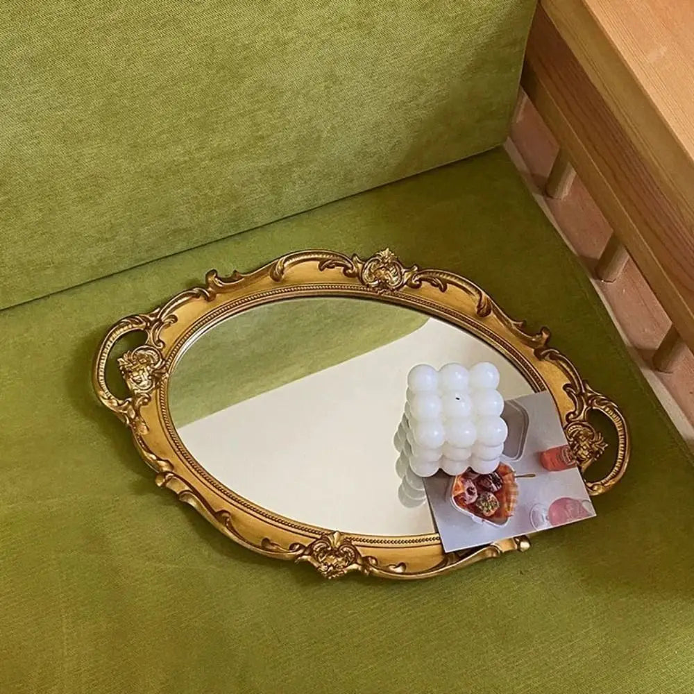 Plateau miroir ovale French vintage Nesty - Modèle doré sur canapé en velours vert, avec bougie et photo