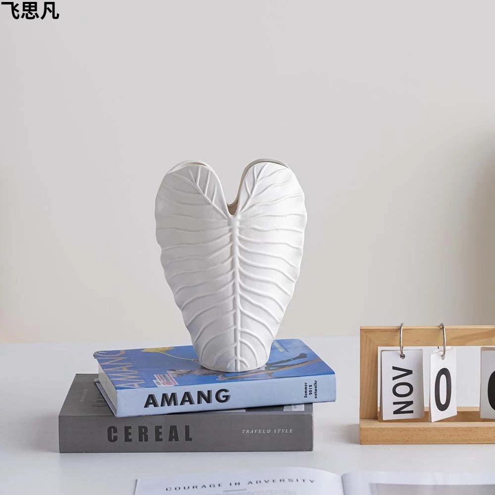 Vase en porcelaine texturé feuille cœur, finition mate Nesty, taille blanche vide, posée sur des livres empilés avec un calendrier perpétuel à côté