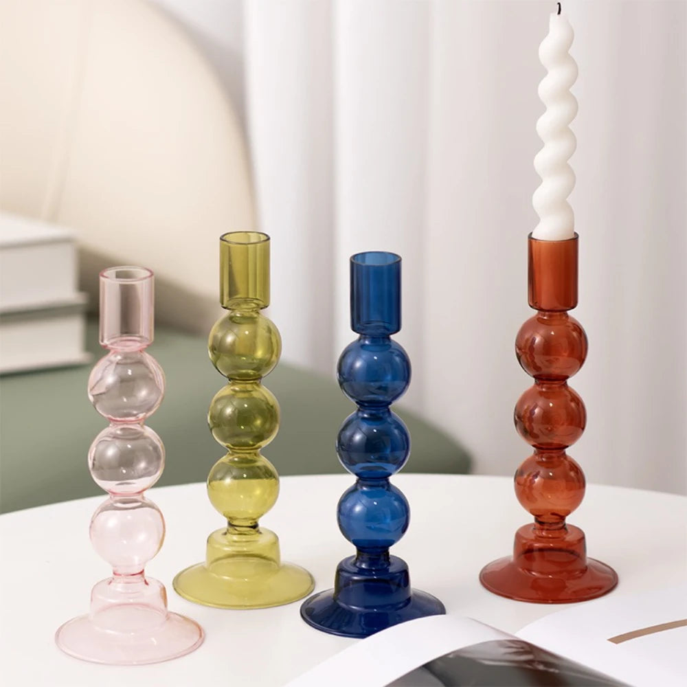 Bougeoir en verre coloré translucide Nesty - Quatre modèles à perles empilées rose, vert olive, bleu et orange, avec bougie torsadée blanche allumée