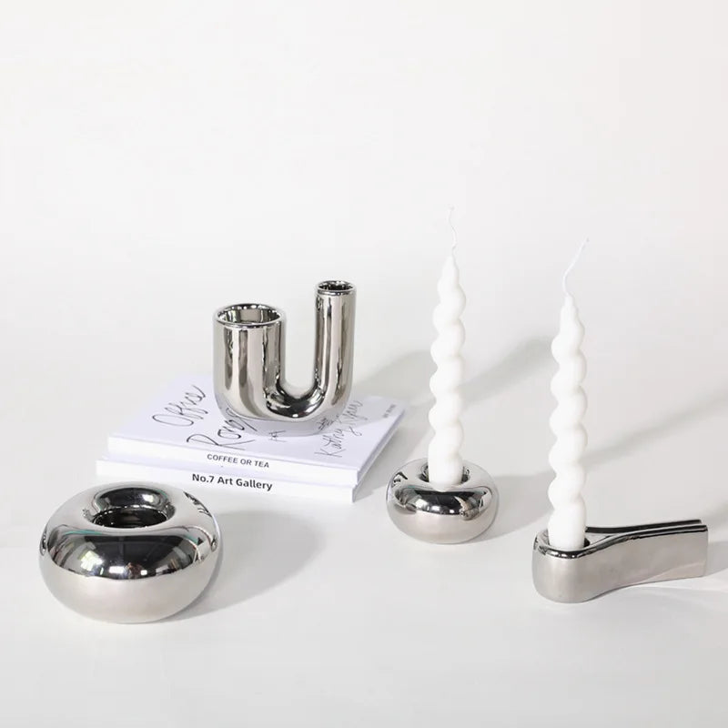 Bougeoir en céramique effet argenté Nesty - Quatre bougeoirs chromés de formes variées (en U, galet rond, bougies torsadées) sur fond blanc