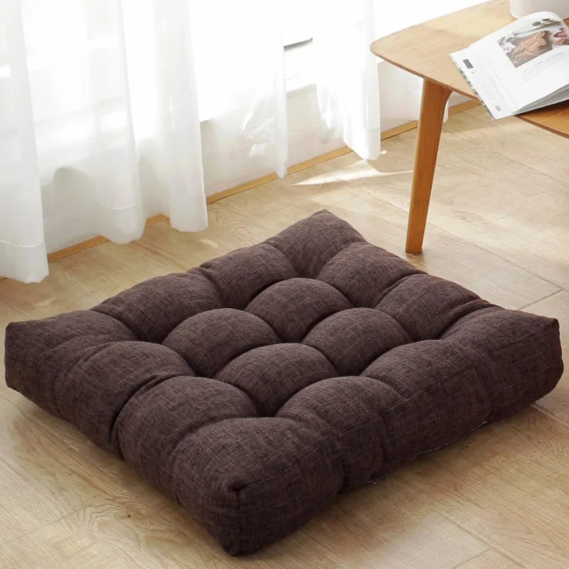 Grand coussin de sol carré tufté en lin, esprit futon, épais Nesty, coussin de sol carré capitonné marron foncé, posé au sol près d'une table basse en bois