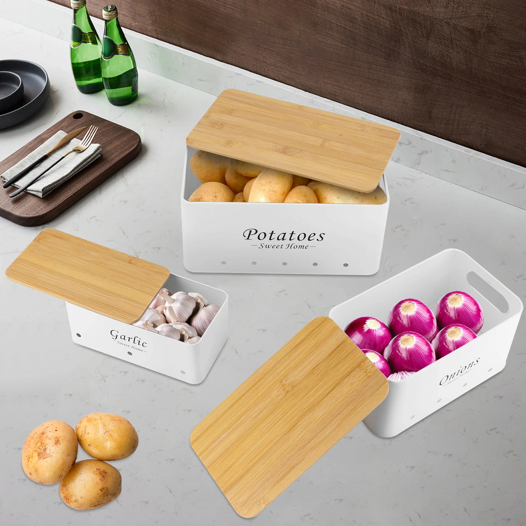 Set de 3 boîtes de rangement ventilées, couvercles en bambou Nesty, coloris blanc, boîtes Potatoes, Garlic et Onions ouvertes garnies, sur plan de travail marbré avec bouteilles vertes