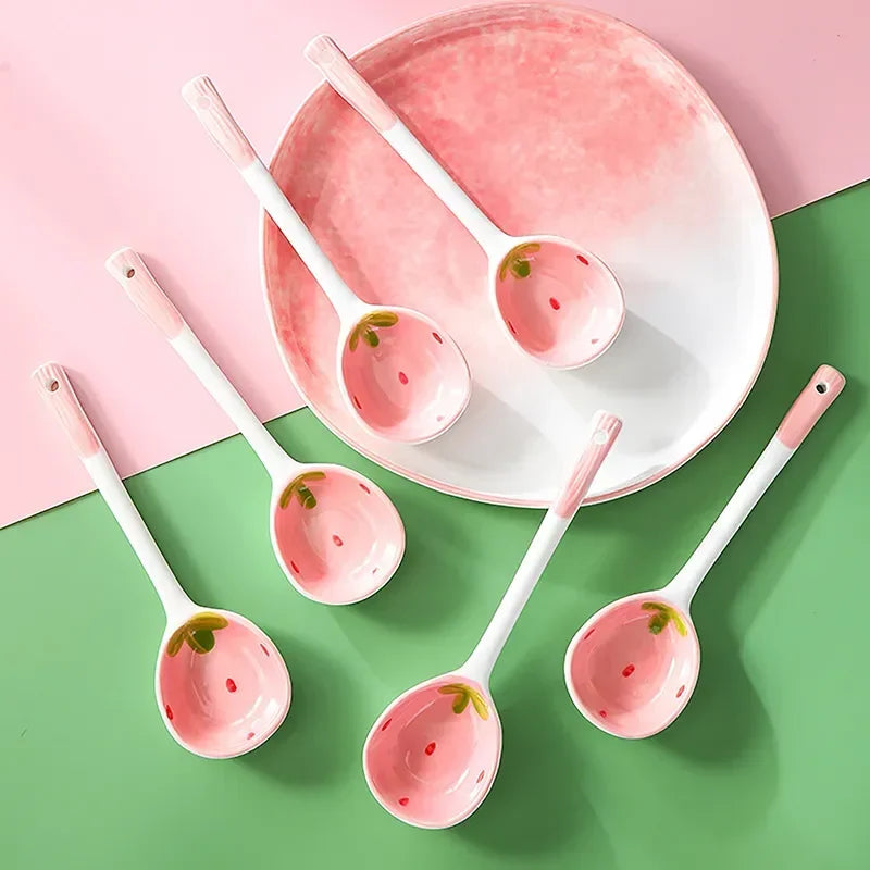 Cuillère en céramique fraise, modèle mignon Nesty, cinq cuillères disposées sur un fond bicolore rose et vert avec une assiette rose