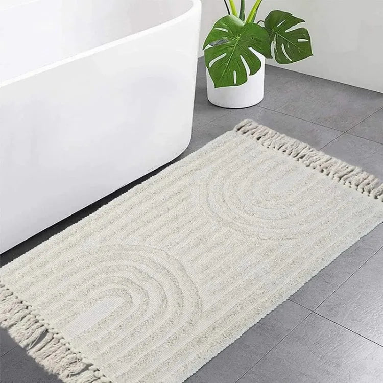 Tapis tufté en coton — tissé à la main - Nesty, variante à motif arches en relief posée dans une salle de bain près d'une baignoire et d'un monstera
