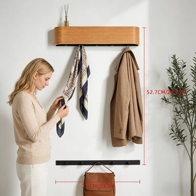 Patère murale en bois de noyer, entrée ou couloir Nesty, femme ajustant un foulard suspendu à une patère avec crochets noirs, manteau accroché à côté, dimension 52,7 cm