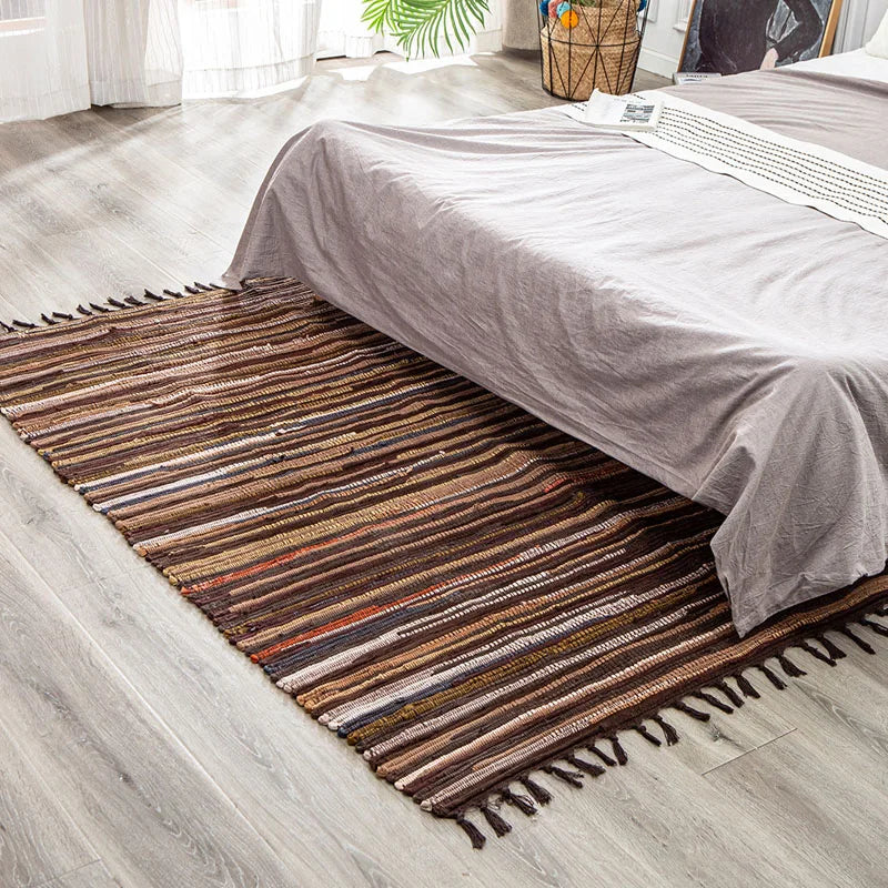 Tapis à franges tissé main — motif rayé - Nesty, variante à rayures multicolores placée sous un lit