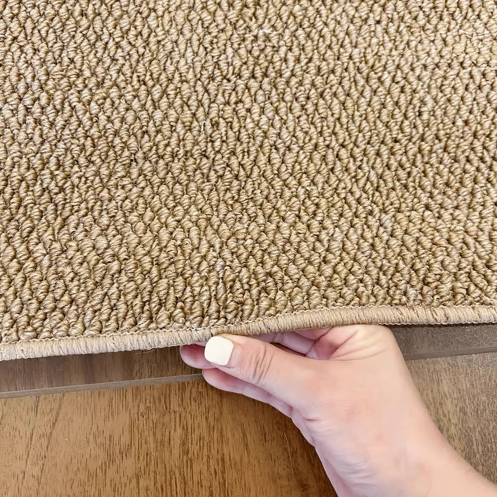 Tapis effet jute tressé, main soulevant le bord pour montrer l'épaisseur du tissage - Nesty