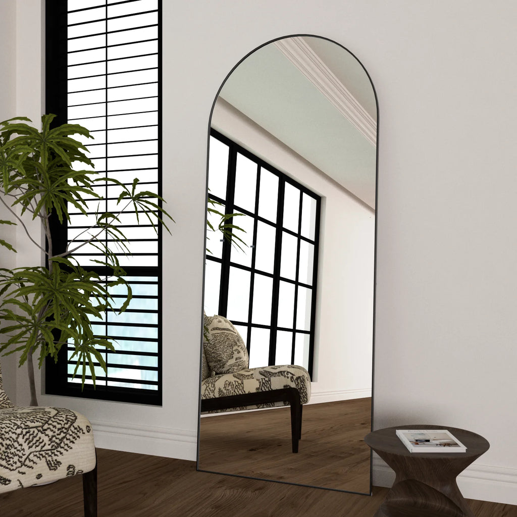 Miroir psyché cintré Nesty - Cadre noir, posé au sol, reflet d'un fauteuil imprimé et d'une table d'appoint