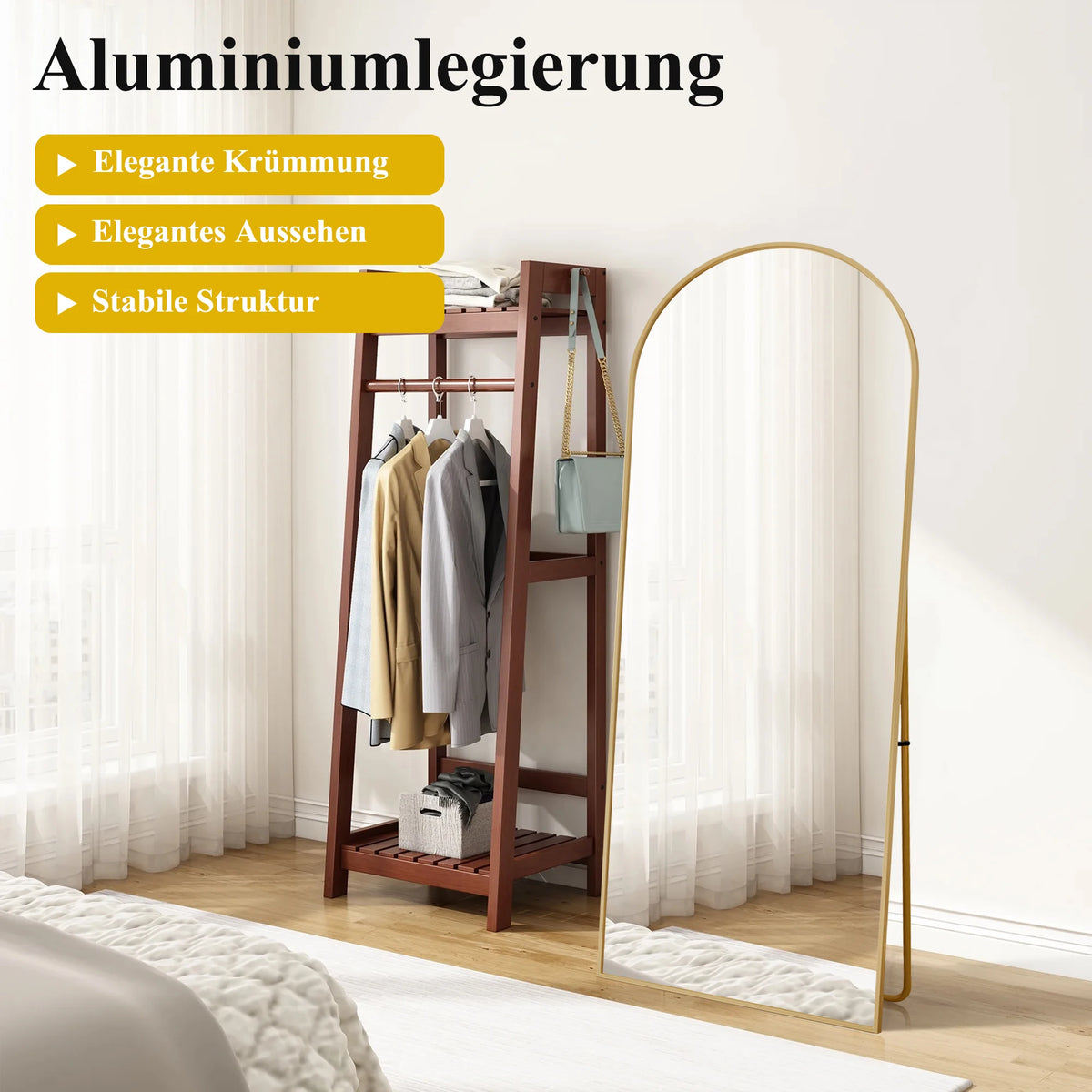 Miroir psyché incurvé Nesty - Cadre doré près d'un portant à vêtements en bois, visuel publicitaire en allemand