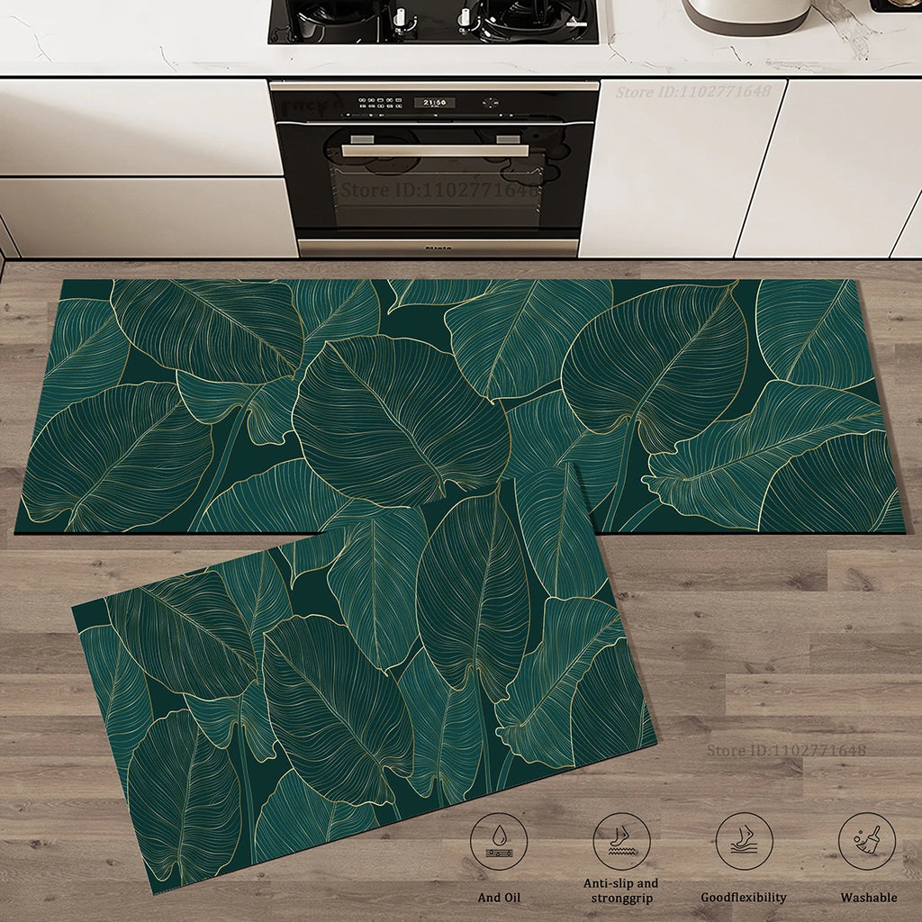 Deux tapis de cuisine assortis à motif de feuilles tropicales aux contours dorés sur fond vert foncé, posés devant une cuisinière et un four encastré.