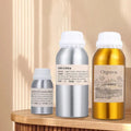 Recharge huile parfumée pour diffuseur Nesty - Trois flacons en aluminium argenté et doré, tailles 100 à 500 ml, sur console en bois