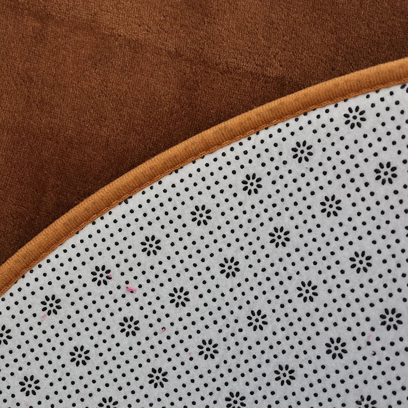 Gros plan sur le bord d'un tapis rond en velours marron, montrant l'envers antidérapant à motif de pois blancs.