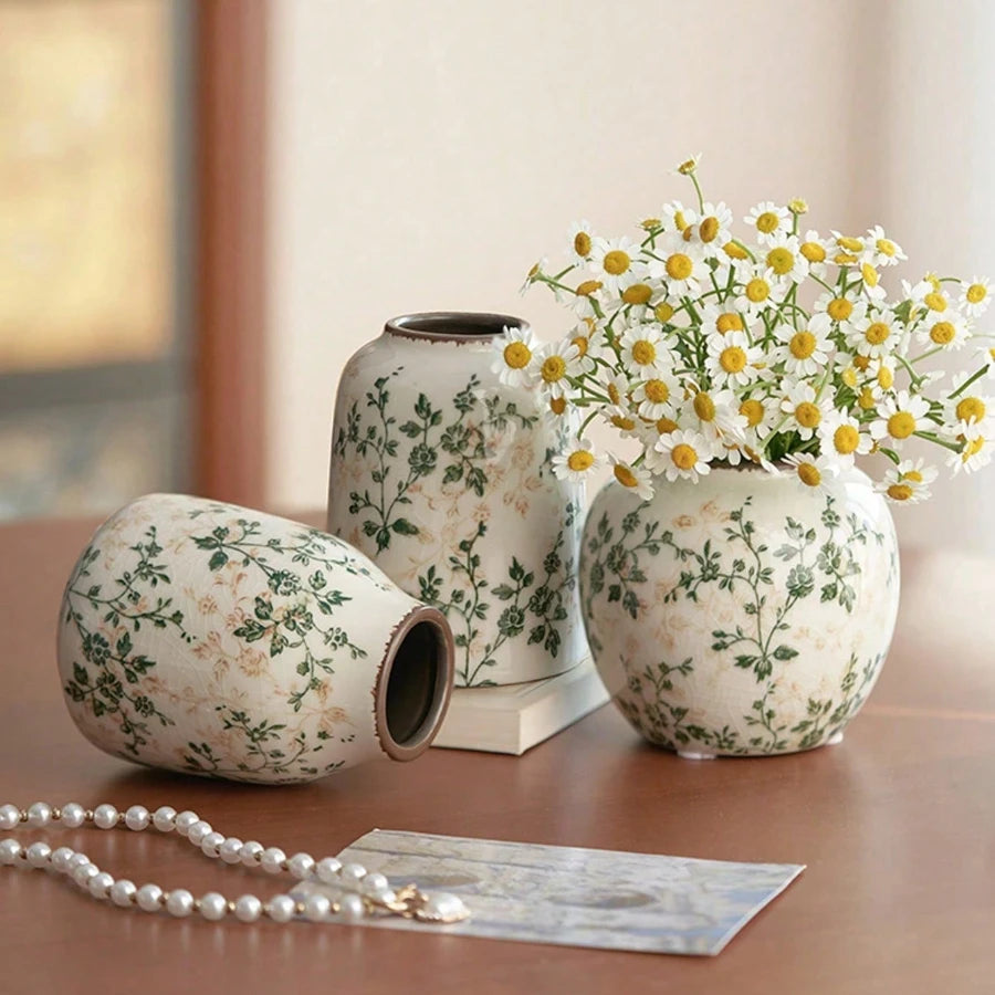 Vase en céramique craquelé, fait main, esprit bohème Nesty, trois mêmes vases craquelés à motif floral, l'un couché garni de marguerites blanches, sur table en bois