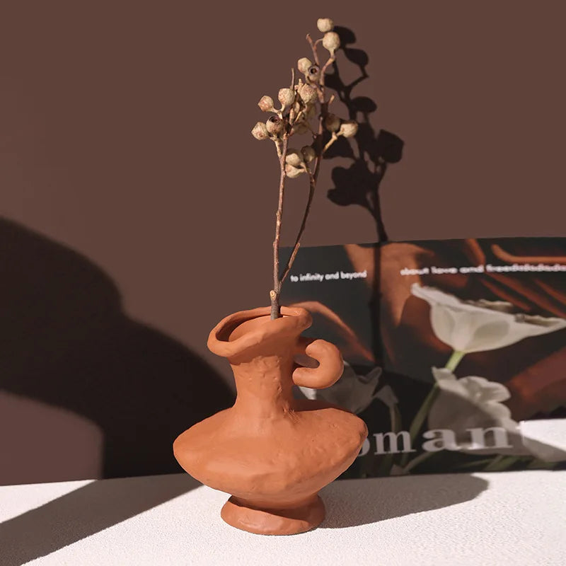 Vase céramique artistique, style nordique rétro - Nesty - Vase terracotta à petite anse recourbée, garni de baies séchées, posé sur une table près d'un magazine ouvert