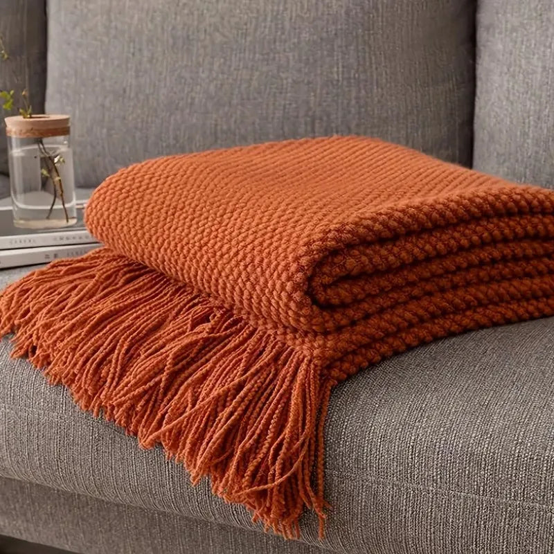Plaid tricoté terracotta Nesty - Plié sur canapé gris, texture gaufrée à picots et longues franges