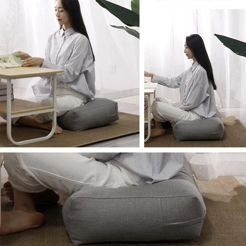 Housse de coussin de dossier en lin, sans garnissage, tête de lit Nesty, femme assise en tailleur adossée à un coussin cale dossier gris, sur tapis en jonc devant une table basse
