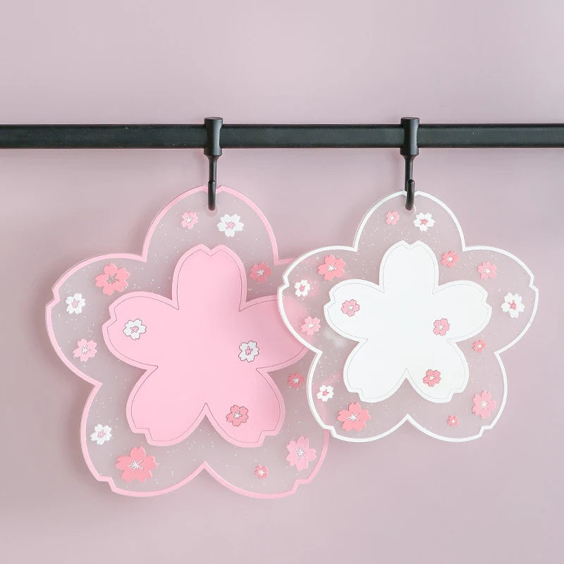 Deux dessous de verre en silicone fleurs de cerisier, coloris rose et blanc, suspendus à des crochets sur une barre - Nesty