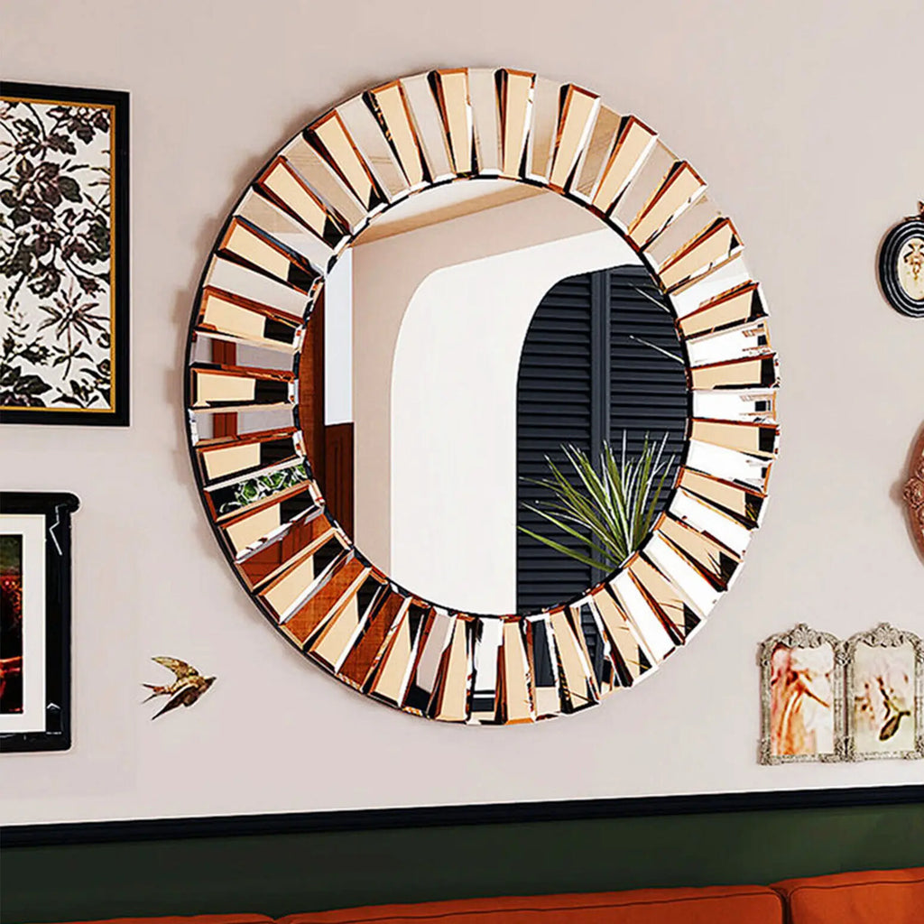Grand miroir rond soleil à segments biseautés dorés et argentés, sur mur avec cadres décoratifs et canapé orange - Nesty