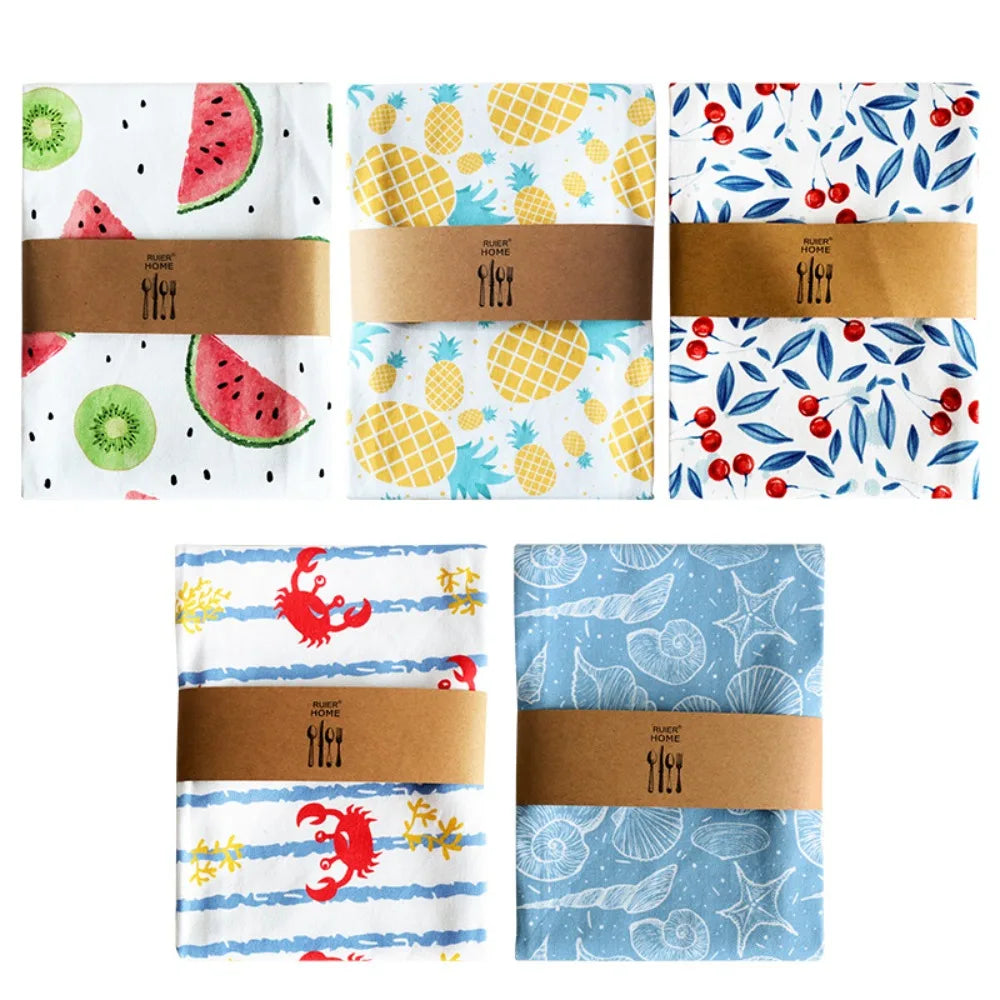 Cinq torchons en coton pliés et cerclés d'un bandeau kraft, motifs pastèque-kiwi, ananas, cerises, crabes et coquillages - Nesty
