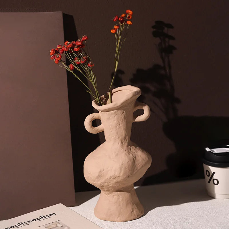 Vase céramique artistique, style nordique rétro - Nesty - Vase en terre cuite beige à anses asymétriques, garni de branches de baies rouges séchées, en contre-jour près d'un gobelet