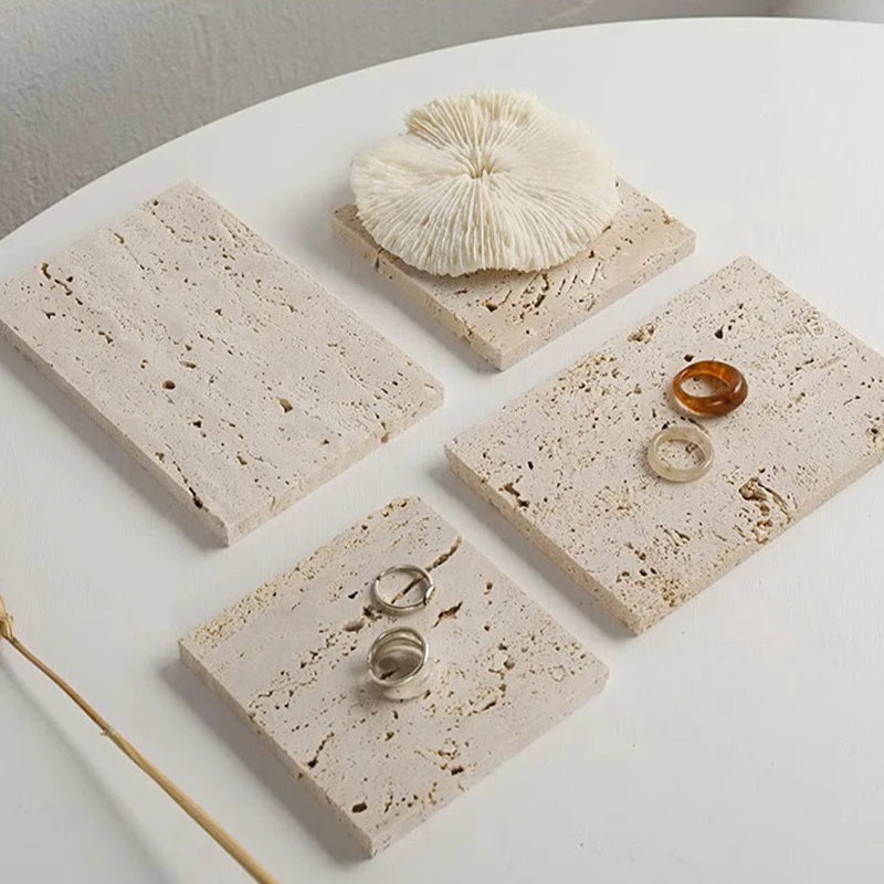 Vide-poche en travertin Nesty - Quatre plaques avec bagues et corail décoratif sur table blanche