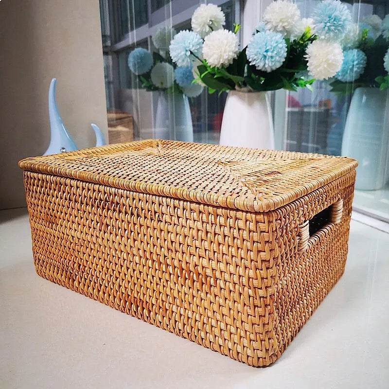 Boîte de rangement carrée en rotin tressé avec couvercle Nesty, vue en angle sur une console, vase blanc garni de pompons bleu et blanc en arrière-plan