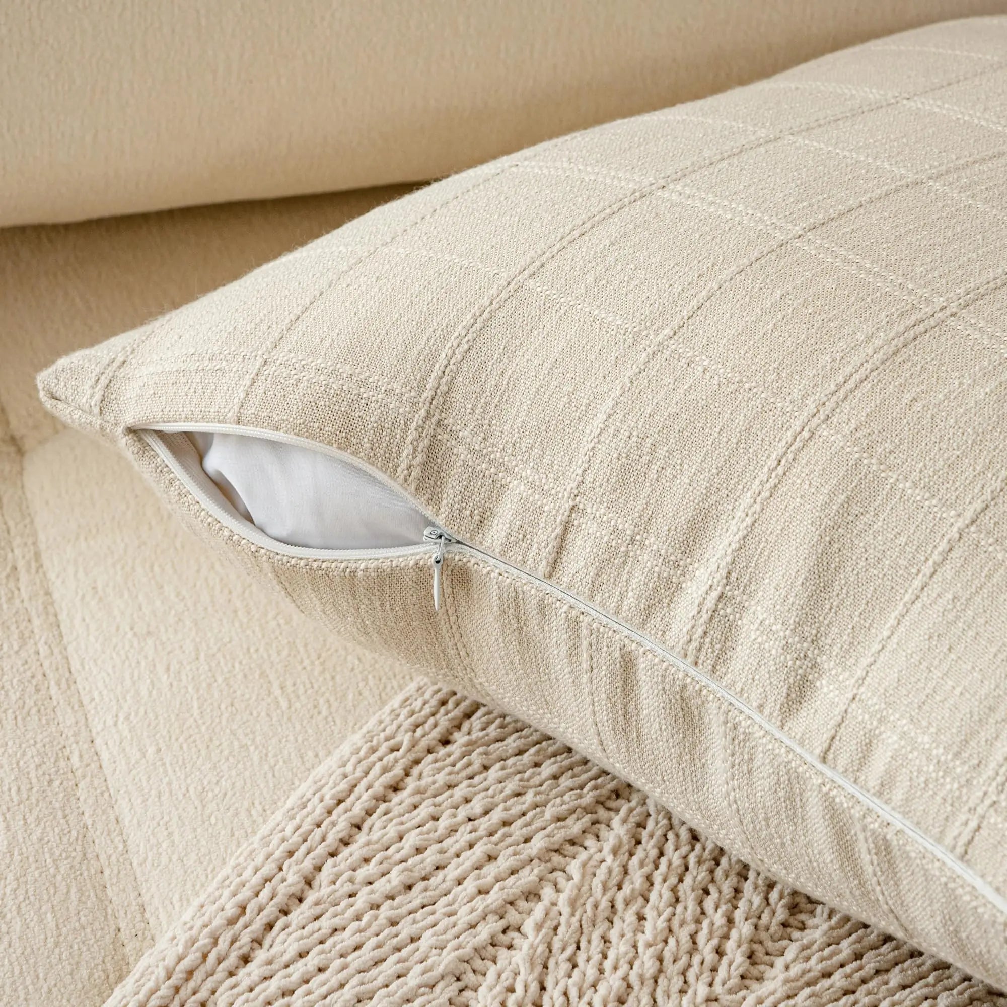 Housse de coussin en lin à carreaux, esprit campagne Nesty, gros plan sur le tissage à carreaux du lin écru et la fermeture éclair d'une housse de coussin