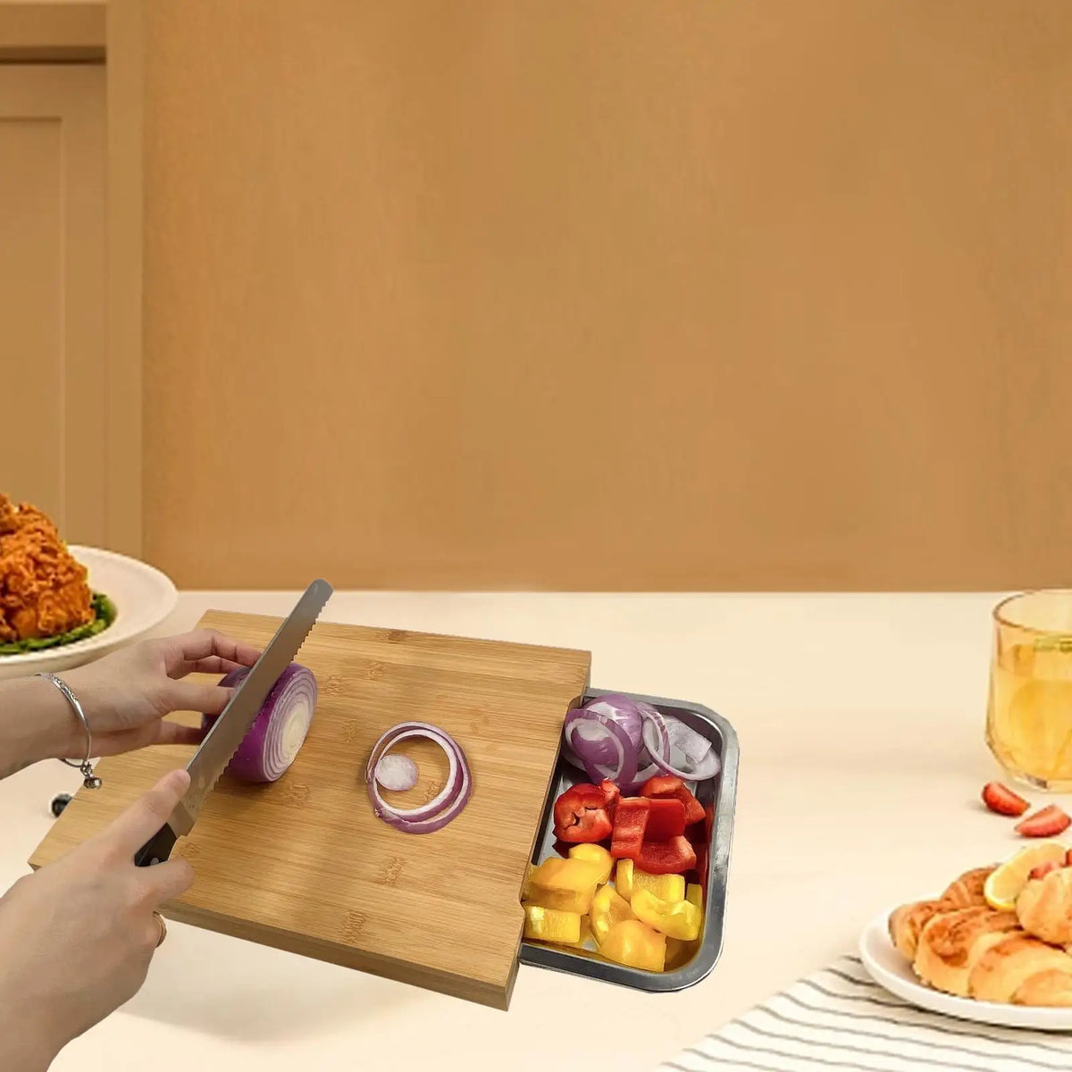 Planche à découper en bois avec plateau de service intégré Nesty, en situation sur une table, assiette de poulet frit et fraises et verre de boisson à côté