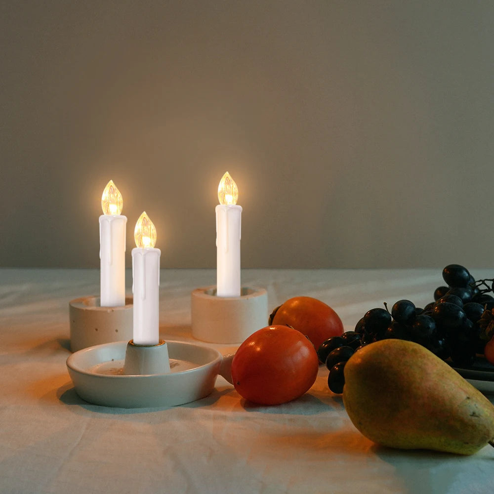 Bougie LED sans flamme, mèche noire, télécommande incluse Nesty, trois bougies LED sur socles en pierre, entourées de fruits (tomates, raisins, poire), ambiance tamisée