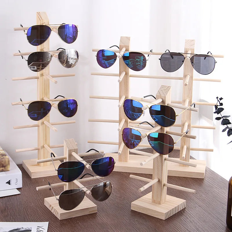 Présentoir à lunettes en bois à plusieurs niveaux Nesty, plusieurs présentoirs en bois clair garnis de lunettes de soleil sur un bureau