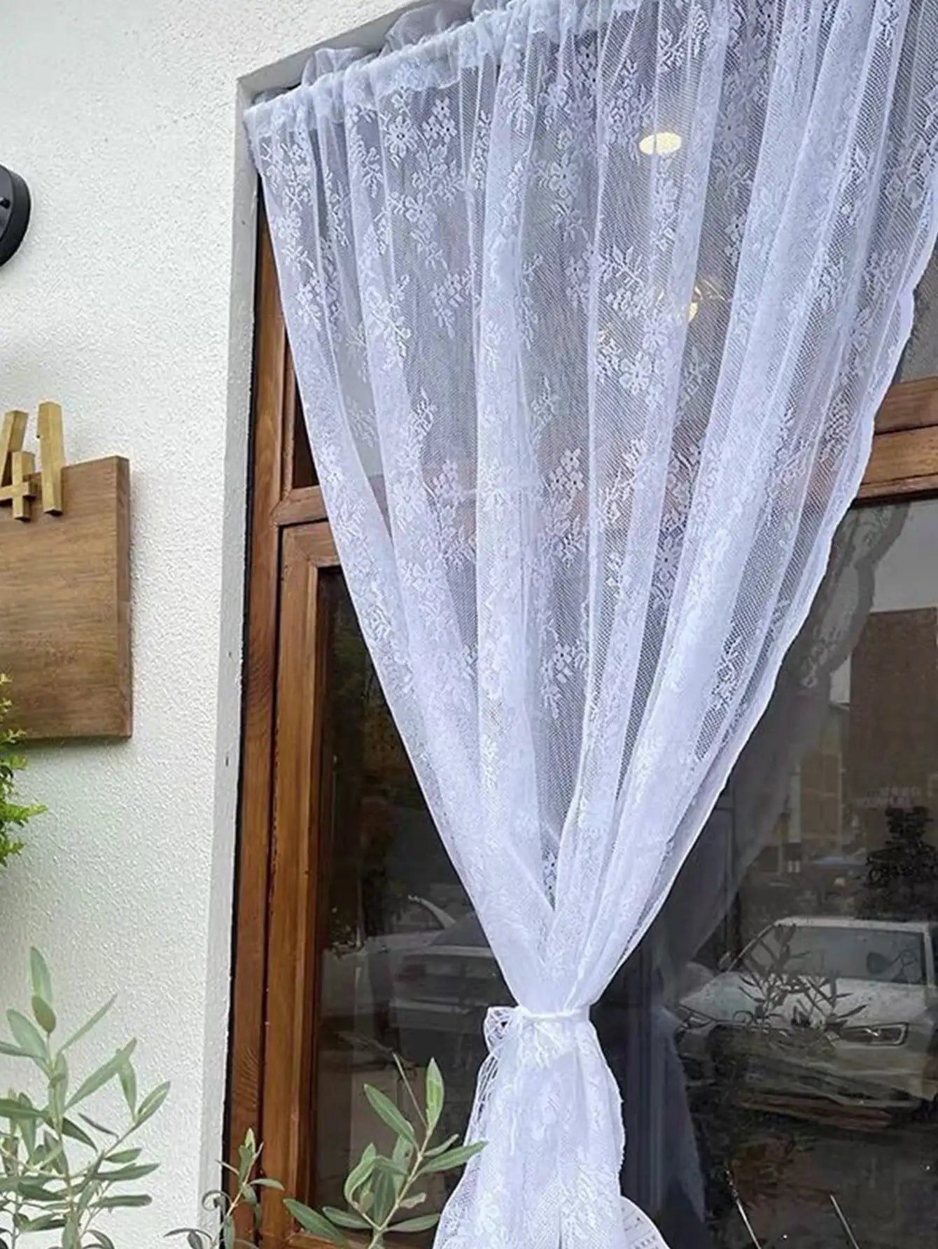 Voilage à motif dentelle florale Nesty - Voilage noué installé sur une porte-fenêtre en bois à l'extérieur
