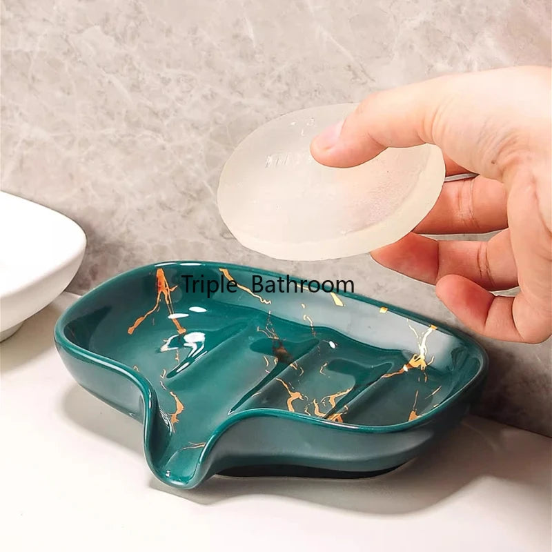 Porte-savon en céramique effet marbre vert et or, main tenant un porte-savon en silicone translucide au-dessus - Nesty