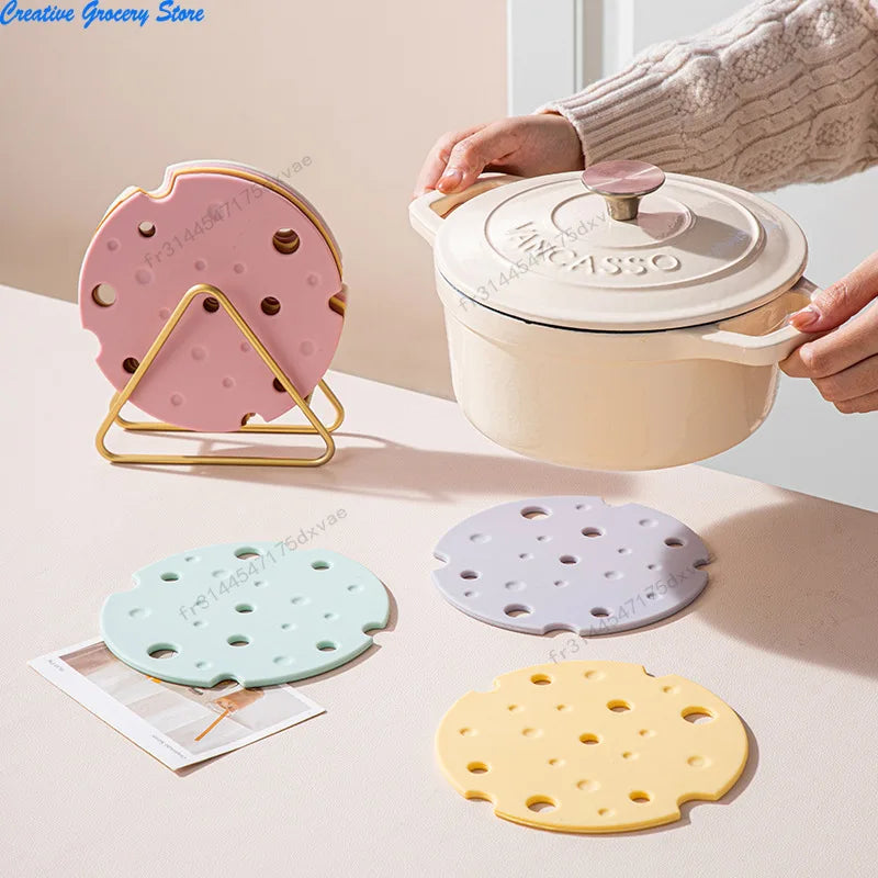 Dessous de plat en silicone forme fromage à trous, coloris rose, vert, violet et jaune, avec cocotte en fonte et présentoir doré - Nesty